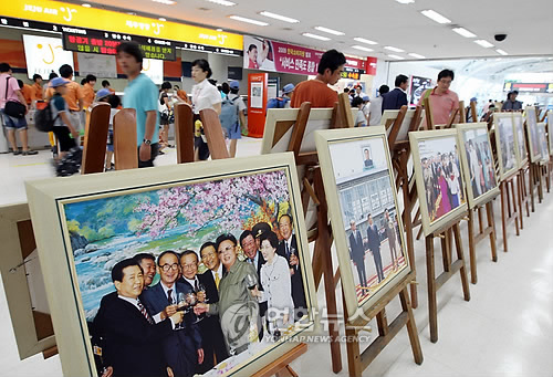 (제주=연합뉴스) 김호천 기자 = 제주국제공항 3층 국내선 출발대합실에서 관광객들이 김대중 전 대통령과 김정일 국방위원장의 남북 정상회담 장면을 담은 사진전시회를 둘러보고 있다. 제주도사진기자회와 인터넷 사진 전문업체인 포토데스크가 김대중 전 대통령을 추모하기 위해 마련한 이번 사진전은 22일부터 30일까지 9일간 열린다. 2009.8.22. khc@yna.co.kr 연합뉴스