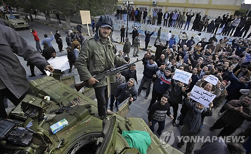 (AP=연합뉴스) 27일(현지시각) 리비아 수도 트리폴리 인근 자위야에서 무장한 한 시민이 정부군으로부터 빼앗은 장갑차 위에 올라서 있다. 자위야에서는 시민 편으로 돌아선 정부군의 힘을 얻은 수백 명의 반정부군이 이날 무아마르 카다피 국가원수 측근 세력의 반격에 대비했다. 연합뉴스