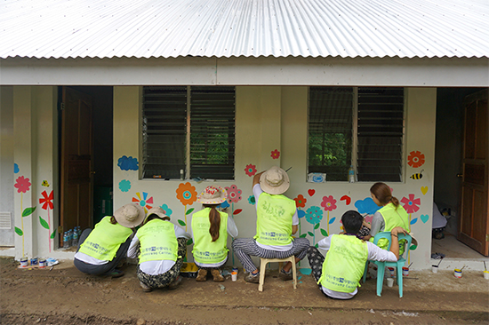 국외봉사 참여학생들이 바디앙 초등학교 건물 외벽에 벽화를 그리는 노력봉사를 하고 있다. 계명카리타스봉사센터